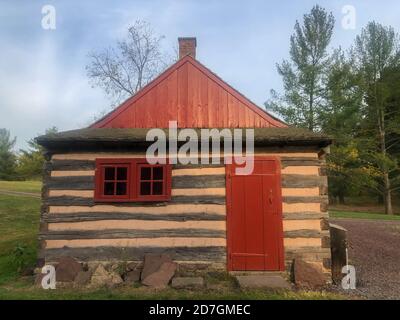 Colonial Pennsylvania Blockhütte mit roter Tür in natürlicher Umgebung. Stockfoto