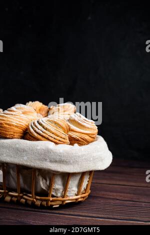 Modernes Gebäck in 2020-Cruffins, eine Mischung aus Croissants und Muffins. Auf einem dunklen Tisch, bestreut mit Puderzucker. Der Blick von oben. In einem Stockfoto