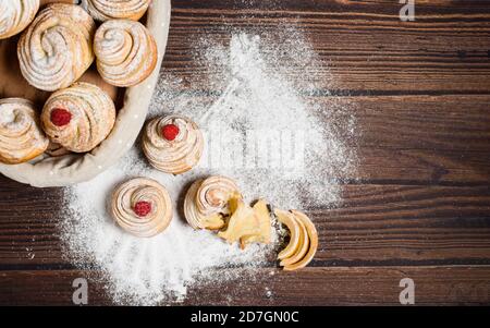 Leckere Cruffins werden aus mehrschichtigen Croissants in Form eines Bun hergestellt. Muffins auf dunklem Holzgrund, bestreut mit Puderzucker und Raspel Stockfoto