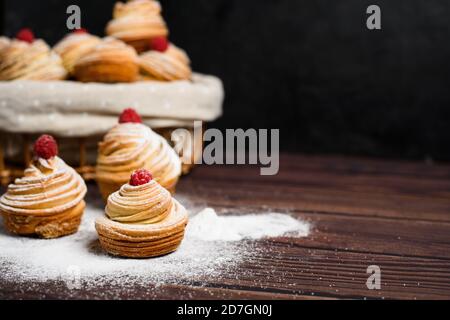 Moderne Cruffins werden aus Blättercroissants in Form eines Muffins hergestellt. Auf dunklem Grund in Puderzucker. Platz kopieren. Die Ansicht von oben. clos Stockfoto