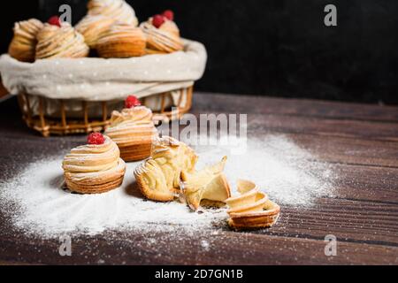 Moderne Cruffins werden aus Blättercroissants in Form eines Muffins hergestellt. Auf dunklem Grund in Puderzucker. Platz kopieren. Die Ansicht von oben. clos Stockfoto