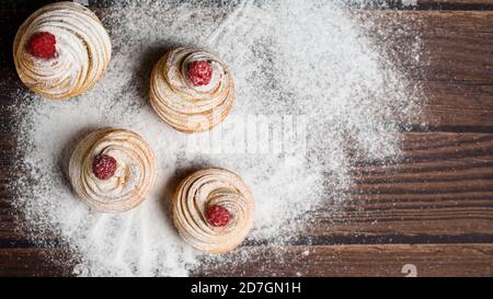 Leckere Cruffins werden aus mehrschichtigen Croissants in Form eines Bun hergestellt. Muffins auf dunklem Holzgrund, bestreut mit Puderzucker und Raspel Stockfoto