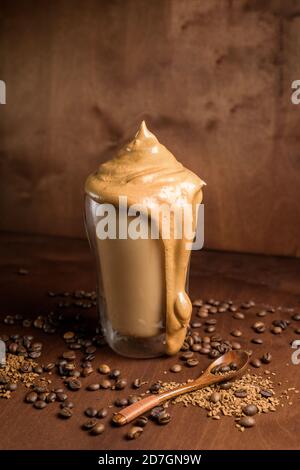 Kalter Dalgon-Kaffee in klaren Gläsern auf dunklem Holzhintergrund. Schaum aus Zucker und Instantkaffee wird mit einem Mixer über kalte Milch geschlagen. Koreanisch und Stockfoto