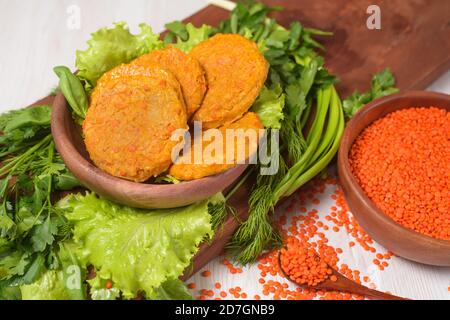 Vegane Linsen Burger in Holzplatte mit grünem Salat auf hellem Hintergrund. Vegetarisch gesundes Essen. Linsen in Holzplatte. Der Blick von der t Stockfoto