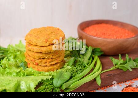 Vegane Linsen und Karotten-Burger in einem Holzteller mit grünem Salat auf hellem Hintergrund. Vegetarisch gesundes Essen. Linsen in einem Holzteller. Stockfoto