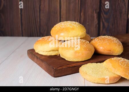 Frische leckere Hamburger Brötchen sind mit Sesamsamen bestreut. Auf dunklem Holzgrund. Nahaufnahme. Platz für Text. Stockfoto