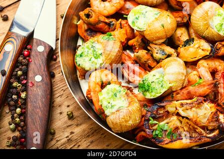 Gegrillte Garnelen, Muscheln und gefüllte Schnecken in der Pfanne Stockfoto