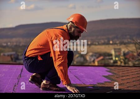 Erbauer verwenden Dachziegel, professionelles Reparaturdach. Einbau des Flachdachs. Dachdecker in besonderer Schutzkleidung. Neues Dach im Bau Wohnhaus. Alles sollte perfekt sein. Stockfoto