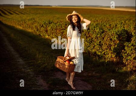 Mädchen in Strohhut und mit Weidenkorb auf Johannisbeerfeld Hintergrund. Stockfoto