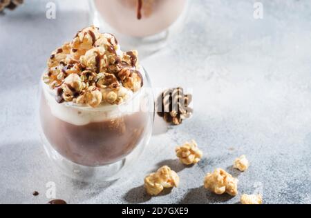 Kalte Schokolade Dessert mit Schlagsahne, Popcorn und Karamell Topping in Gläsern auf beigem Hintergrund, Platz für Text Stockfoto