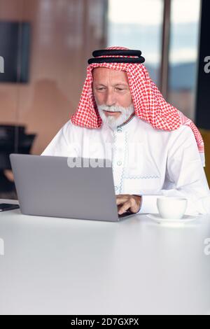 Arabischer Geschäftsmann zuversichtlich und lächelnd im Büro mit Laptop. Stockfoto