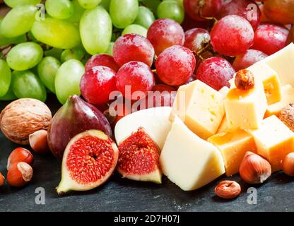 Snack-Teller für Wein: Käse, grüne und rosa Trauben, Feigen, Nüsse und Honig, selektive Fokus Stockfoto