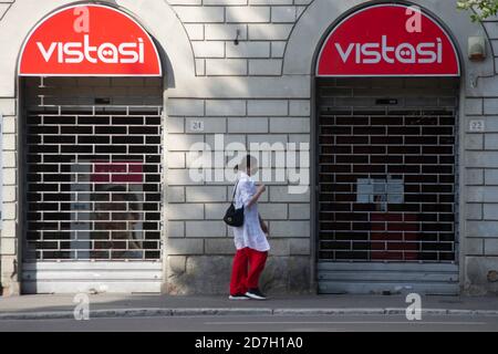 Mädchen in roten Hosen und Maske geht auf dem Bürgersteig Einer Stadtstraße neben einem Laden mit rot Schilder Stockfoto
