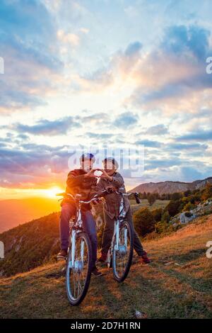 Aktives Senior-Paar auf Fahrrädern, die Herzform mit Händen und küssen. Stockfoto
