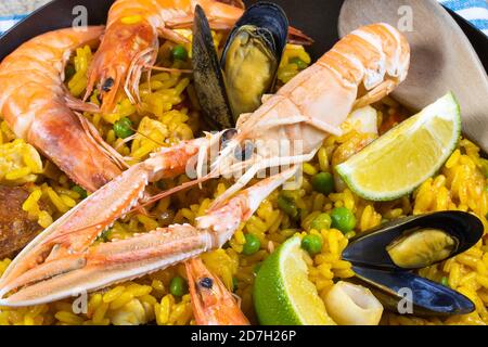 Pfanne gefüllt mit Paella auf einem Holztisch Stockfoto
