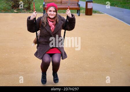 Junge Frau sitzt auf Schaukel im Herbst Park Stockfoto