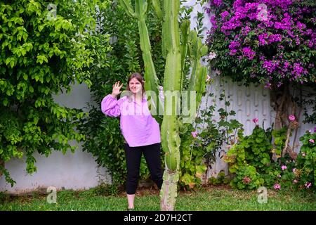 Eine Frau zeigt ihre Hände hinter einem hohen Kaktus Stockfoto