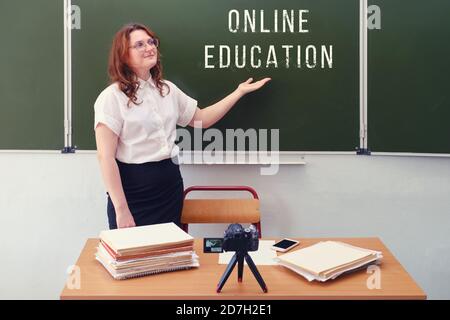 Eine Lehrerin führt Online-Schulungen durch, die im Klassenzimmer stehen und Videos auf einer Kamera drehen. Schulbildung über das Internet durch die coro Stockfoto