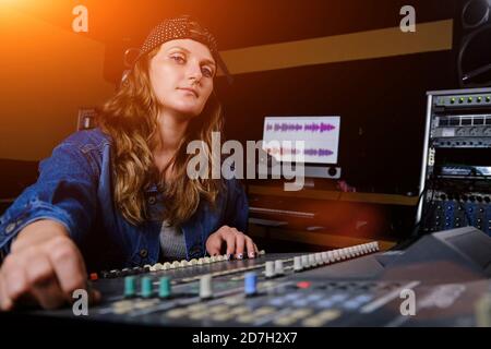 Eine Frau steuert den Sound-Mixer. Die Frau an der Fernbedienung im Aufnahmestodio. Professionelle Gesangsaufnahmen im Studio. Stockfoto