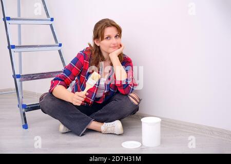 Eine Malerin sitzt mit einem Pinsel in der Hand an einer weißen Wand, Raum kopieren Stockfoto
