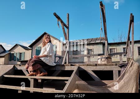 Eine Frau sitzt auf den Stufen eines leeren Gerüsts Mit Galgen in einer amerikanischen Stadt des wilden Westens Stockfoto
