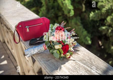 Hochzeitsbouquet mit roter Tasche und schwarzer Sonnenbrille Stockfoto