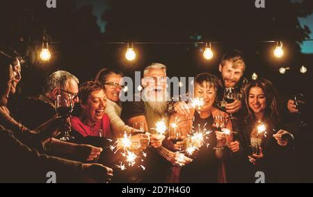 Glückliche Familie feiert mit Wunderkerzen Feuerwerk bei Nacht Party - Gruppe von Menschen mit unterschiedlichen Alters und Ethnizität Spaß haben Gemeinsam Stockfoto