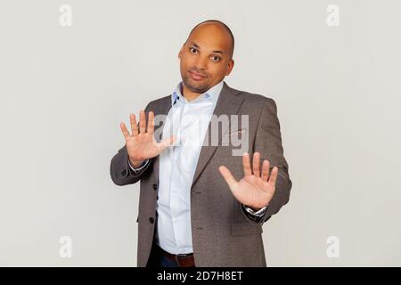 Portrait des jungen afroamerikanischen Mannes Geschäftsmann zeigt Palmen, zeigt Mangel an Verantwortung, seine Hände heben, verwirrt, Gefühl unschuldig. Stehen auf einem grauen Hintergrund Stockfoto