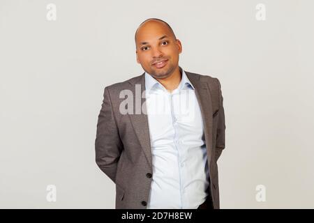 Porträt eines jungen afroamerikanischen Mannes Geschäftsmann lächelnd, posiert Blick in die Kamera. Eine positive Person. Stehen auf einem grauen Hintergrund Stockfoto
