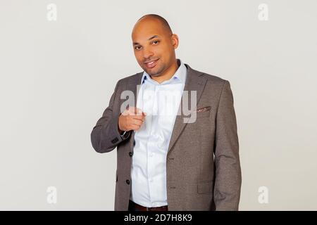 Porträt des jungen afroamerikanischen Kerl Geschäftsmann zeigt mit Zeigefinger auf die Kamera und lächelt hell. Stehen auf einem grauen Hintergrund Stockfoto