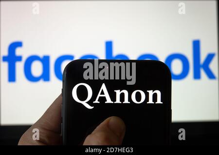 QAnon im Vergleich ZU FACEBOOK. QAnon-Unternehmenslogo auf dem Smartphone, das auf Facebook-Logos platziert ist. Konzept für das Verbot von QAnon in sozialen Medien. Stockfoto