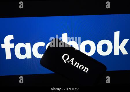 QAnon im Vergleich ZU FACEBOOK. QAnon-Unternehmenslogo auf dem Smartphone, das auf Facebook-Logos platziert ist. Konzept für das Verbot von QAnon in sozialen Medien. Stockfoto