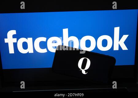 QAnon im Vergleich ZU FACEBOOK. QAnon-Unternehmenslogo auf dem Smartphone, das auf Facebook-Logos platziert ist. Konzept für das Verbot von QAnon in sozialen Medien. Stockfoto