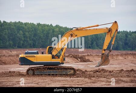 Der moderne Raupenbagger fährt durch ein schlammiges Feld Stockfoto