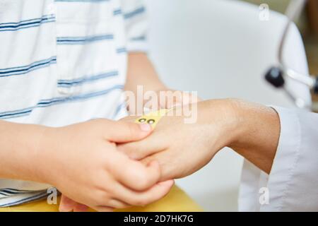 Kind klebt Gips auf der Hand des Kinderarztes als ein Übung gegen Angst Stockfoto