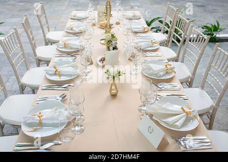 Schöne und elegante Outdoor-Tischanordnung für eine Hochzeit, ein Abendessen oder eine Party mit hohen Gläsern, weißem porzellan und Besteck Stockfoto