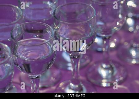 Elegante Wassergläser auf violettem Tisch serviert, Nahaufnahme, Draufsicht Stockfoto