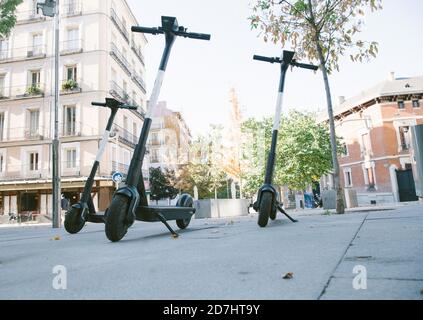 Niedriger Winkel der modernen Elektroroller auf der Straße geparkt Sonniger Tag in Madrid Stockfoto