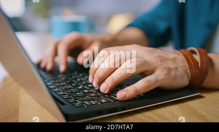Nahaufnahme eines Mannes, der im Home Office auf einem Laptop tippt. Stockfoto