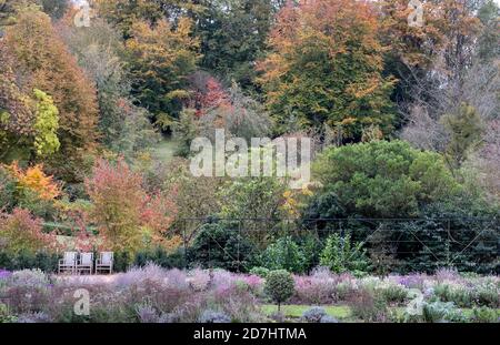 Formelle Gärten im Dyrham Park, Gloucestershire. Drei Holzgartenstühle in einer Reihe unten links auf dem Foto. Fotografiert im Herbst. Stockfoto