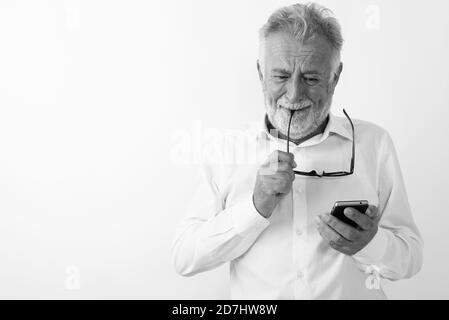 Studio shot von Sad älterer bärtiger Mann weinte, während Sie Handy und beißen Brillen vor weißem Hintergrund Stockfoto