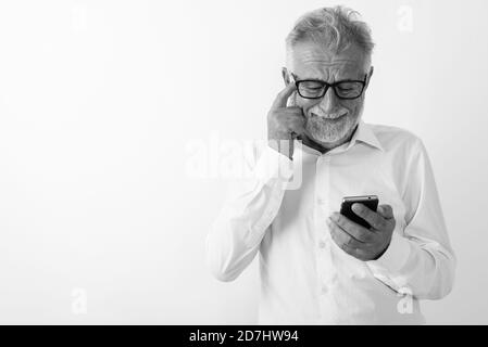 Studio geschossen von traurigen älteren bärtigen mit Handy während Kratzen Kopf mit Brille vor weißem Hintergrund Mann Stockfoto