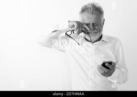 Studio geschossen von traurigen älteren bärtigen mit Handy während Schreien und Holding Brillen gegen den weißen Hintergrund Mann Stockfoto