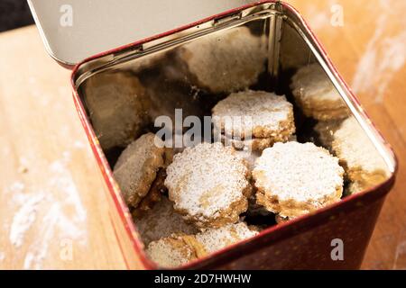 Weihnachtsbacken: Nahaufnahme von Spitzbuben mit Zuckerguss in einer Keksdose. Stockfoto