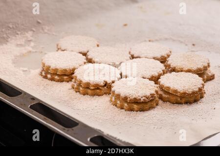 Weihnachtsbacken: Deutsche Marmeladenkekse (Spitzbuben) mit Zuckereier auf Backpapier Stockfoto