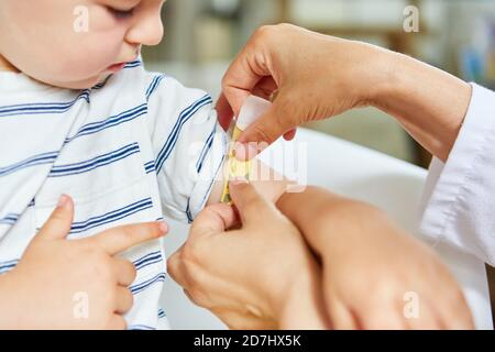 Das Kind bekommt als Behandlung einen Pflaster auf seinen verletzten Arm Beim Kinderarzt Stockfoto