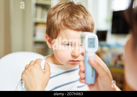 Kinderarzt mit dem Infrarot-Stirnthermometer zur Messung des Kinders Fieber ohne Kontakt Stockfoto