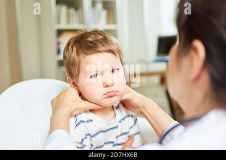 Kinderarzt palpatates Lymphknoten und Mandeln bei einem Kind mit Halsschmerzen Stockfoto