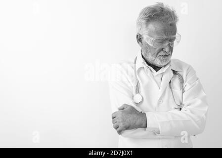 Studio shot von Sad älterer bärtiger Mann Arzt denken beim Tragen von Brillen mit Waffen gegen weißen Hintergrund gekreuzt Stockfoto