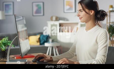 Porträt der schönen jungen Frau, die an Mobile Application Design auf ihrem Personal Computer zu Hause arbeitet. Stockfoto